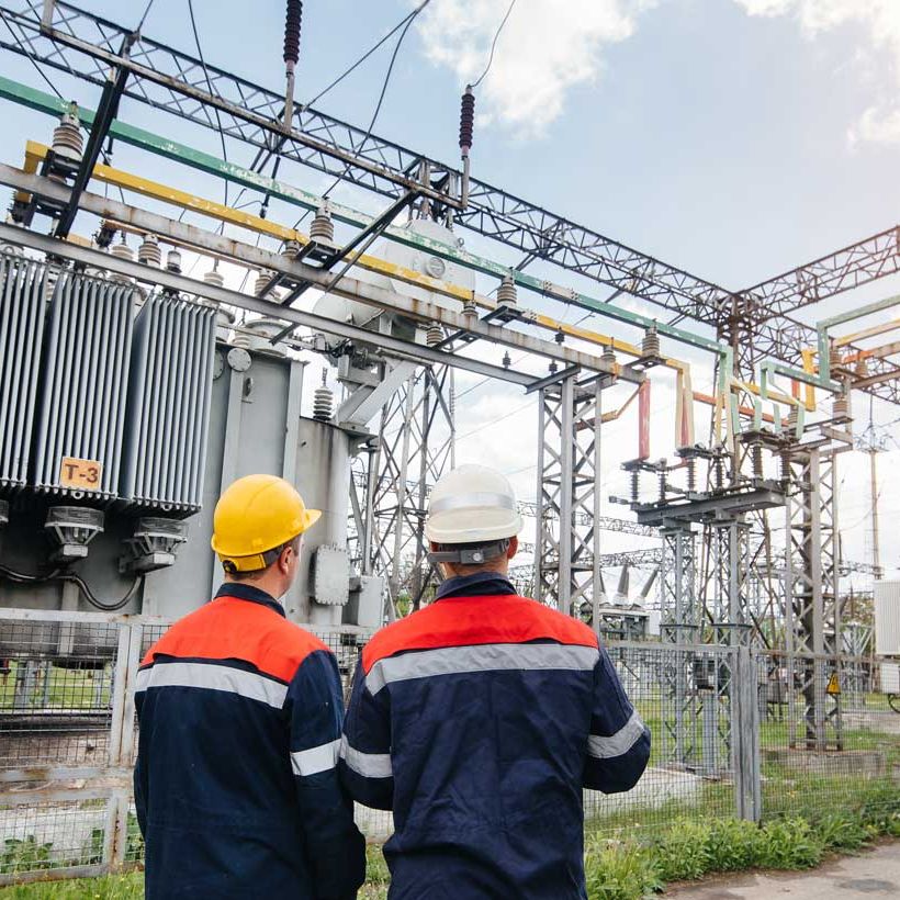 wo specialist electrical substation engineers inspect modern high-voltage equipment during sunset. Energy. Industry